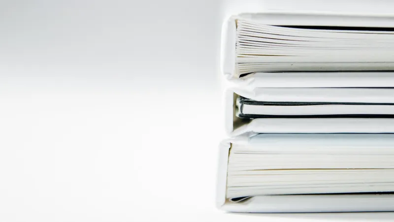 A neat stack of thick document folders on a clean white surface