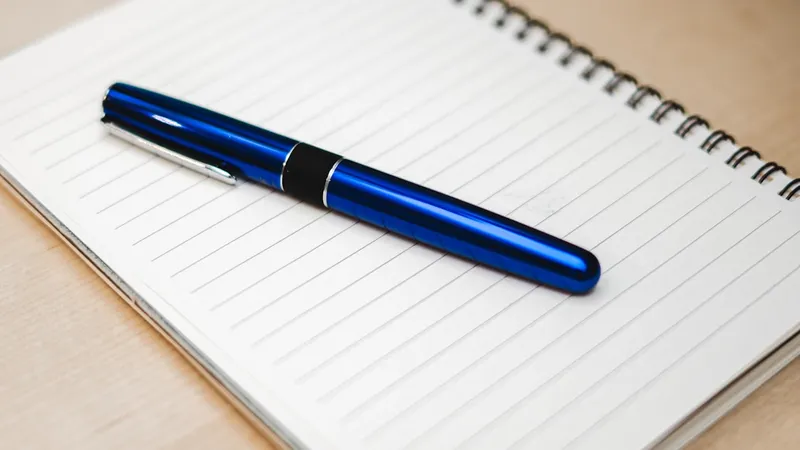 Ballpoint pen resting diagonally across an open notebook on a minimal desk