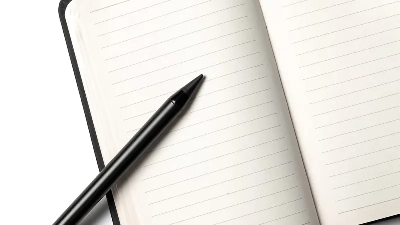 A notebook with a pencil resting on top, photographed against a clean white background